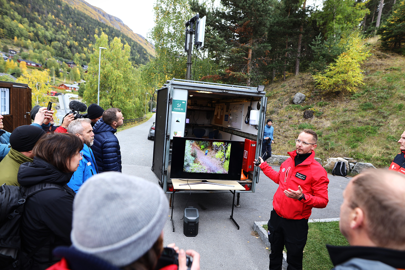 Man presenting video on screen to an audience outside